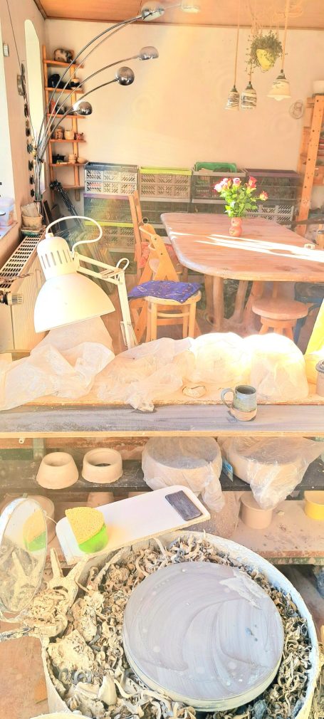 Ein gemütlicher Raum mit Holzstühlen, einem Tisch und Blumenarrangement. Werkzeuge sind sichtbar.