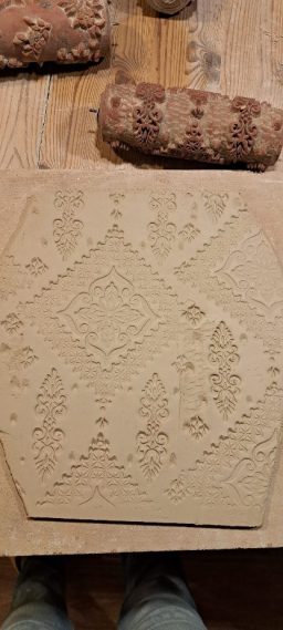 Abdruck eines Musters auf Ton, umgeben von Holzformen.