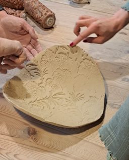 Handgefertigte Babybauchschale mit kunstvollem Reliefmuster auf einem Holztisch.