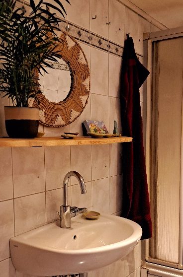 Ein helles Zimmer mit einem Holztisch, Vasen mit Blumen und Regalen im Hintergrund.