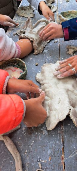Hände formen mit Ton, daneben eine Schüssel mit Material.