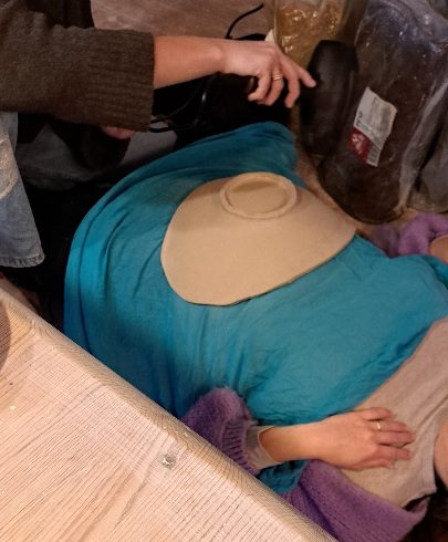 Handgefertigte Babybauchschale mit filigranem Muster aus Ton, umgeben von Händen, die sie halten.