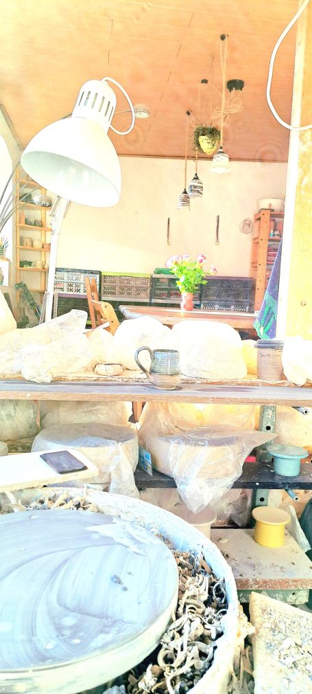 Helle Küche mit Pflanzen, Geschirr und einer Lampen, unordentlicher Arbeitsbereich.