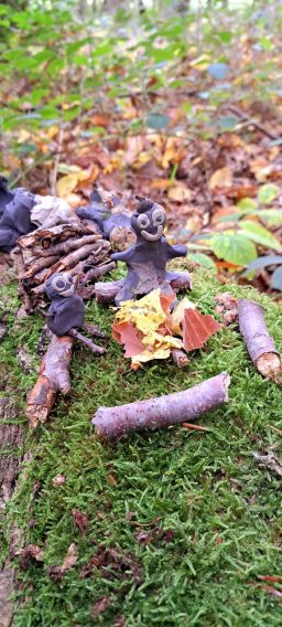 Herbstliche Naturaufnahme mit Laub, Zweigen und Pilzen auf moosbedecktem Boden.