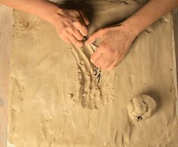 Hände formen und bearbeiten Ton auf einer künstlerischen Arbeitsfläche.