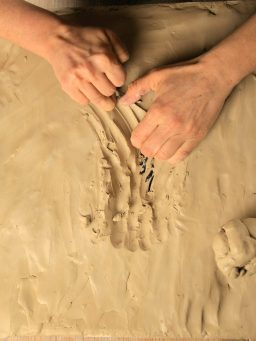 Hände formen und gestalten Ton auf einer glatten Oberfläche.