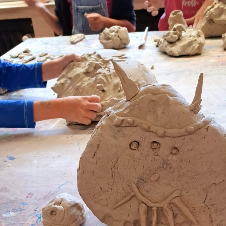 Kinder formen mit Ton Figuren und Skulpturen auf einem Tisch.