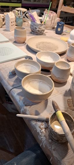 Töpferwaren in verschiedenen Formen und Größen auf einem Werkstatttisch.