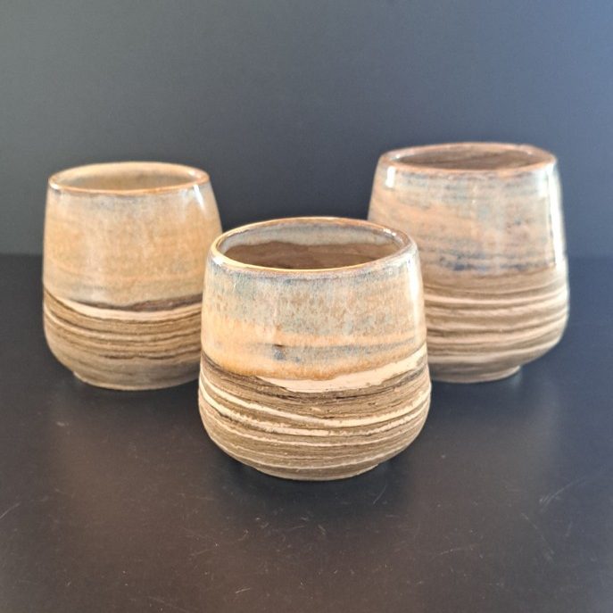 Drei keramische Töpfe mit geschichteter, natürlicher Oberflächenstruktur.