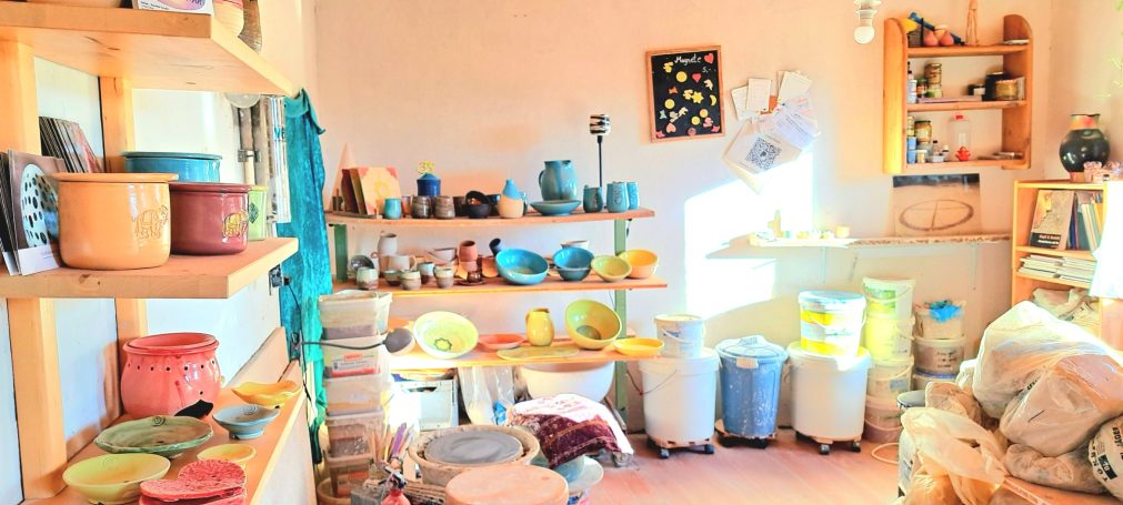 Heller Raum mit Regalen voller Töpferwaren und bunten Dekorationsobjekten.
